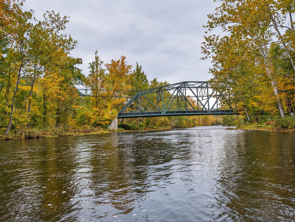 The steel truss bridge at Church Pool above the Farmington River, framed by autumn trees.
